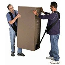 Two movers carrying a large brown box using lifting straps in a studio setting